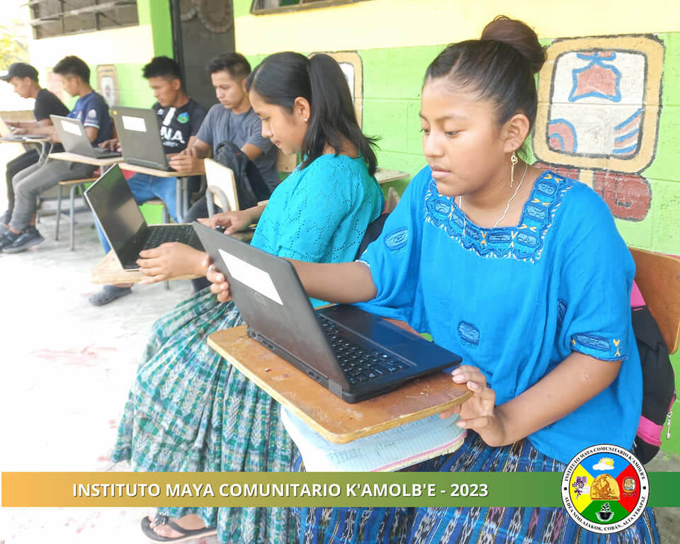 Two girls in traditional indigenous dress using Chaptops computers at Instituto Maya Comunitario K’amolb’e in Guatemala.